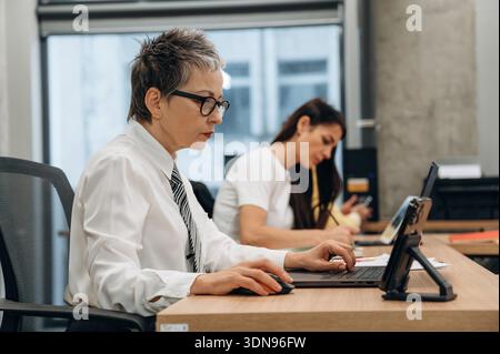 Two business professionals are engaged in collaborative work at a modern office, featuring sleek furniture, technology, and a bright atmosphere that e Stock Photo