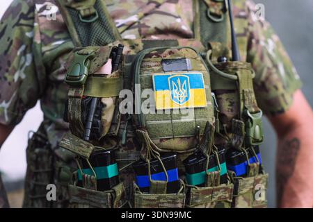 Close up of modern military tactical vest with ammunition pouches and Ukrainian national patch. Detailed view of combat gear, camouflage fabric and eq Stock Photo