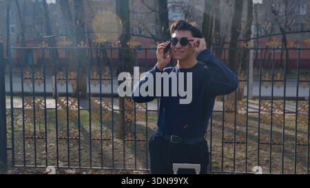 Handsome man standing in park and using smartphone Stock Photo