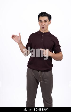 Smiling man in brown shirt pointing aside in studio Stock Photo