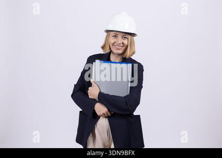 Woman in worker uniform and helmet holding blue folder Stock Photo