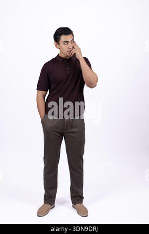 Man standing and thinking with hand near his face Stock Photo