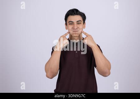 Man in brown shirt touching his face and smiling Stock Photo