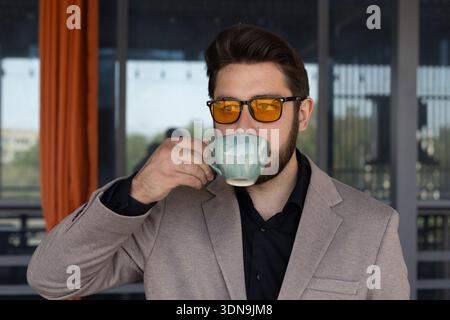 Man holding a cup of coffee and looking away Stock Photo