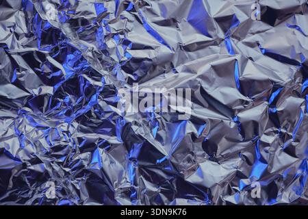 Wrinkled metallic texture creating an abstract pattern with silver and blue highlights Stock Photo