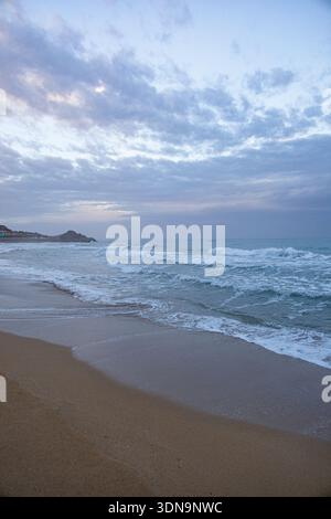 Winter morning on brown sand beach near rough Mediterranean sea and clouds on sky in Northern Cyprus Stock Photo