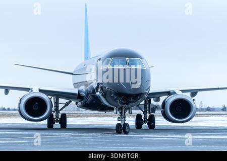 Close-up front view of a black passenger airplane taxiing at winter airport Stock Photo