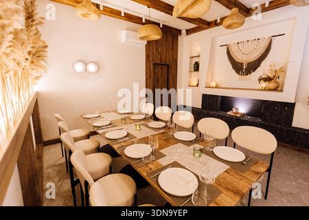 Cozy boho private dining room with long table setting and warm lighting Stock Photo