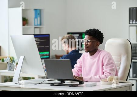 Young Black Man Concentrating on Software Engineering Tasks in Office Stock Photo