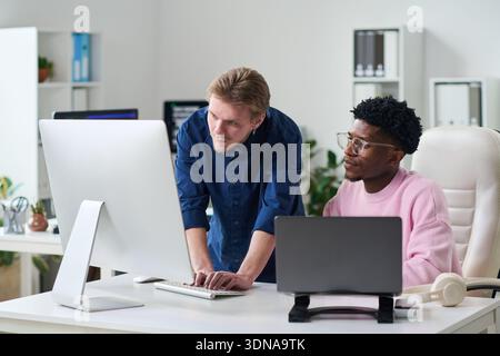 Young Man Explaining Project to Young Black Man in Office Stock Photo