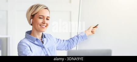 Woman Teaching and Explaining Concepts in a Modern Office Space While Smiling Stock Photo