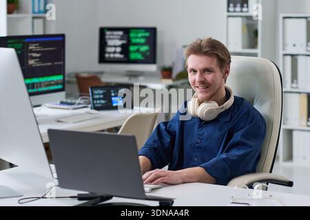 Portrait of Young Man Smiling While Working at Computer Desk Stock Photo