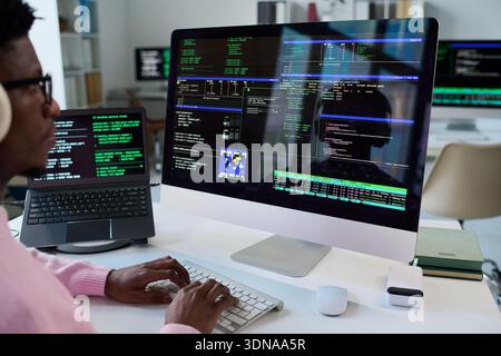 Young Black Man Coding Software on Desktop Computer in Office Stock Photo