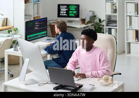 Young Black Man Collaborating with Colleague on Software Development Stock Photo
