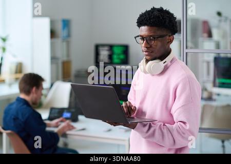 Young Black Man Using Laptop Computer in Office Workspace Stock Photo