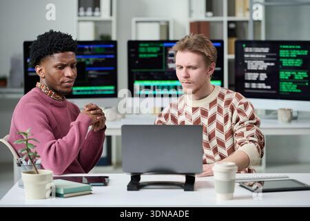 Young Man and Young Black Man Collaborating on Software Development Stock Photo