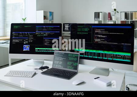 Multiple Computer Monitors Displaying Software Development and Coding Process Stock Photo