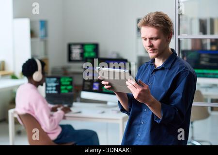Young Man Using Digital Tablet in Office Workspace Stock Photo