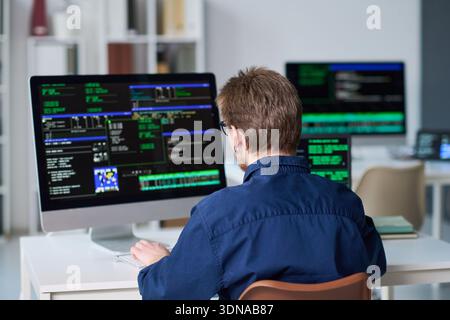 Young Man Working on Computer with Programming Code Displayed Stock Photo