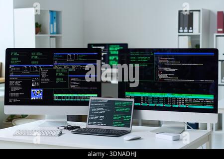 Office Desk Featuring Multiple Monitors Displaying Programming Code Stock Photo