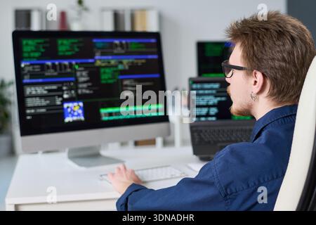 Young Man Writing Code on Computer in Office Setting Stock Photo