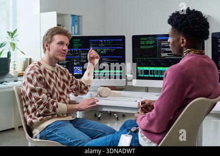 Young Man Explaining Programming Concepts to Young Black Man Stock Photo