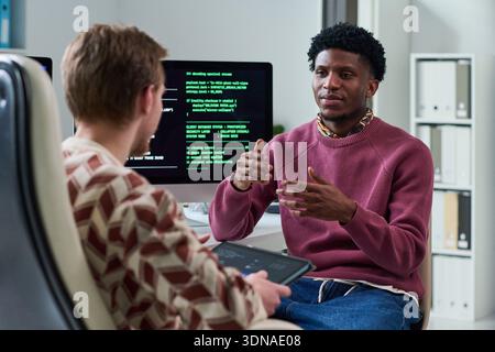 Young Black Man Explaining Software Concepts to Colleague Stock Photo