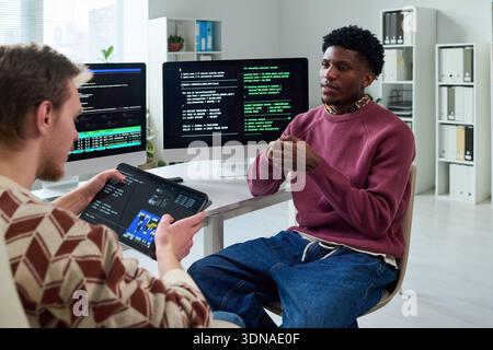 Young Black Man Explaining Programming Concepts to Colleague Stock Photo