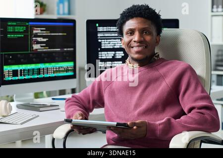 Portrait of Young Black Man Smiling While Using Digital Tablet at Desk Stock Photo