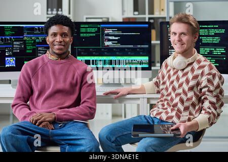 Young Multiethnic Men Collaborating in Office with Computer Screens Stock Photo
