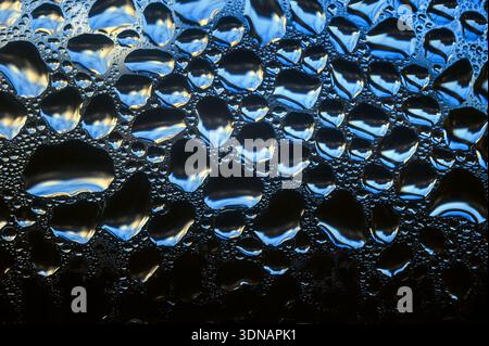 Water droplets on glass in an abstract pattern, with reflections, highly detailed. Stock Photo