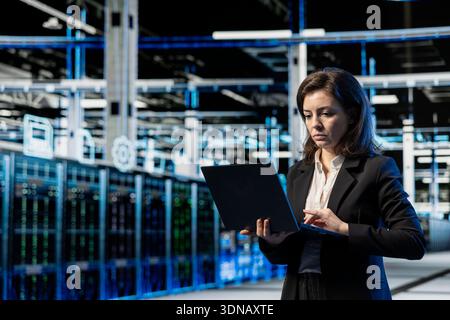 Maintenance, laptop and engineer in data center, VFX compositing overlay. Blue wireframe lines, server farm rackmounts, cloud computing, worker doing system checkup with notebook Stock Photo