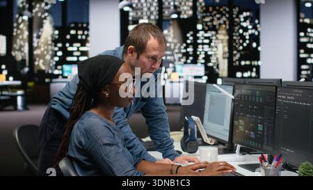 Manager supervising trainee typing code on computer, developing machine learning models to automate tasks in workspace. Team leader and intern writing programming language scripts on PC Stock Photo