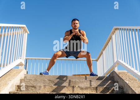 Adult man performing fitness exercise outdoors on sunny day. Stock Photo