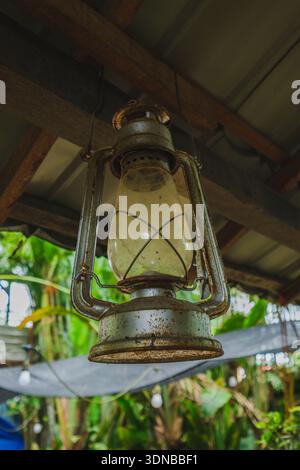 A close-up shot of a weathered, antique hurricane lantern hanging from a wooden beam. This classic kerosene lamp adds a nostalgic, rustic touch to the Stock Photo