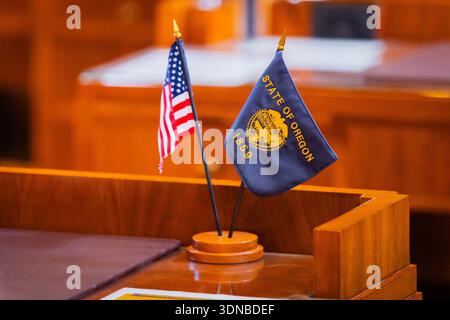 The Oregon State Flag and the American Flag fly side-by-side in a close-up view near the Oregon State Capitol building Stock Photo