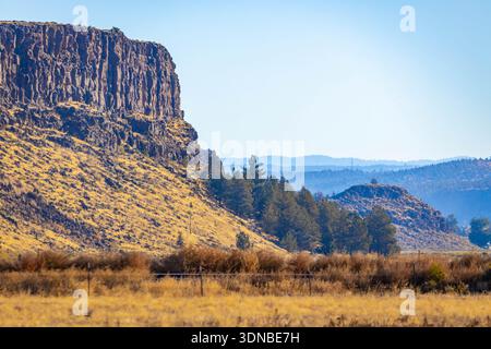 The rugged peaks of the mountain range stretch across the horizon, bathed in sunlight at Smith Rock State Park on a clear summer day Stock Photo