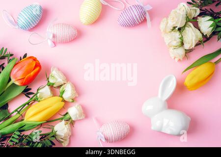 Easter decoration with colorful eggs, flowers and white bunny on pink background. Happy Easter concept. Top view, flat lay, copy space. Stock Photo