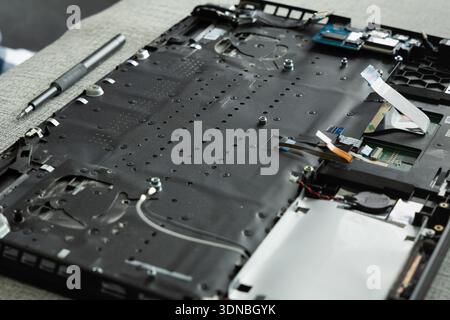 A laptop is open on a table showing its internal parts. The disassembly reveals the motherboard, cooling fans, and other components. Stock Photo