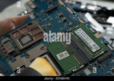 A person works on a circuit board in a technical workshop. The focus is on the memory module and chips. Stock Photo