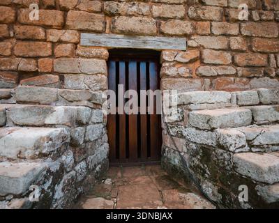 Closeup of an entrance with a wooden door framed by an aged stone and brick wall. Perfect resource for history, architecture, texture, restoration, he Stock Photo