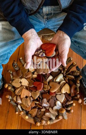 Hands of artist Tommy Simpson holding his handmade wooden hearts - Asheville, North Carolina, USA Stock Photo