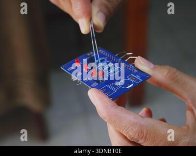 Assembling a printed circuit board using tweezers to place electronic components. Stock Photo