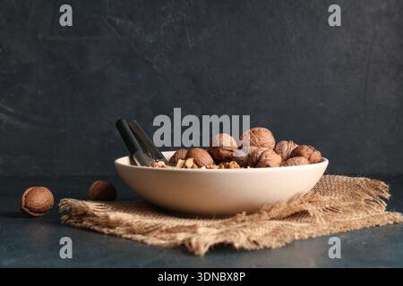 Bowl with tasty walnuts and nutcracker on dark background Stock Photo