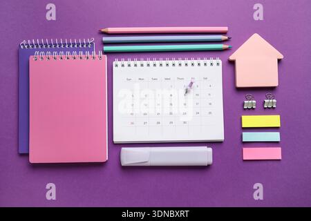 Calendar with office stationery on purple background Stock Photo