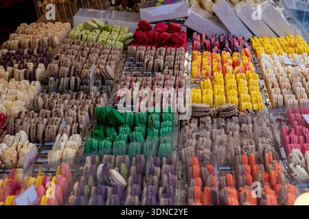 Colorful French macarons are arranged in various flavors and hues, creating an appealing and abundant display of delicious confectionery in a sweet ba Stock Photo