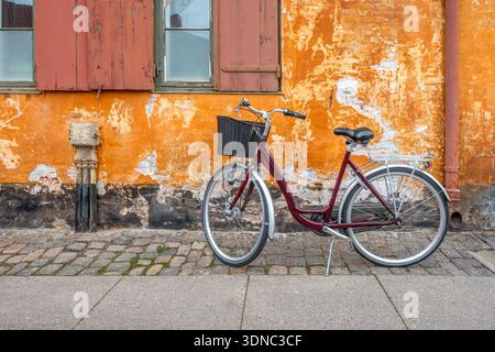 Vintage Bicycle Parked Against Orange Wall in Copenhagen, Nyboder District, Denmark Stock Photo