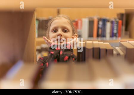 the child chooses books on the shelf. A teenager chooses literature to read. Books on the shelves of a bookstore. Learning from books. The benefits of Stock Photo