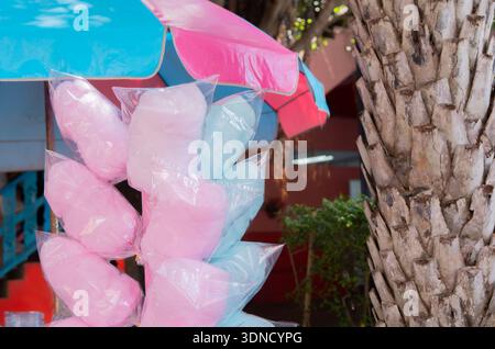 Cotton candy. Candy floss for sale at a wooden kiosk on the street. Sale of sweet food. Pink and blue cotton candy in plastic bags at street market st Stock Photo