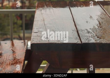 A rustic picnic table wet from recent rain, evoking a peaceful, moody atmosphere. Stock Photo